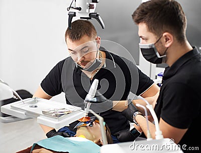Stomatologist looks at patient near his assistant in modern clinic Stock Photo