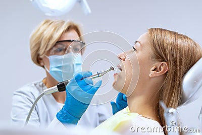 Stomatologist in mask and gloves brushing teeth to patient Stock Photo