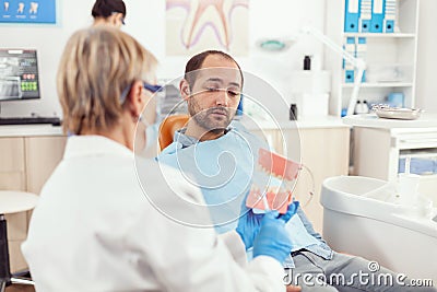 Stomatologist nurse explaining to sick man the surgery using plaster mode Stock Photo