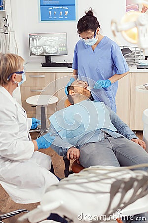 Stomatologist nurse looking in patient mouth preparing for dental surgery Stock Photo
