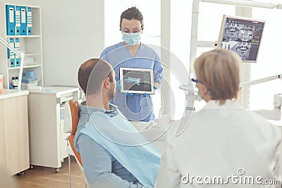 Stomatologist nurse showing tooth x-ray to sick patient explaining treatment Stock Photo