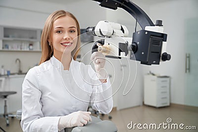 Stomatologist posing in dentistry near dental microscope. Stock Photo