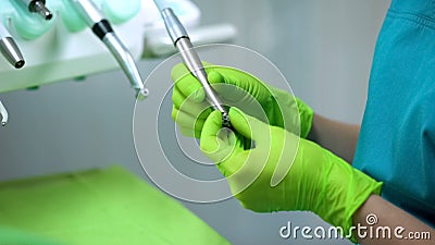 Stomatologist putting drill into handpiece, preparing for procedure, dentistry Stock Photo