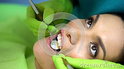 Stomatologist using mirror to examine patients tooth, professional work, closeup Stock Photo