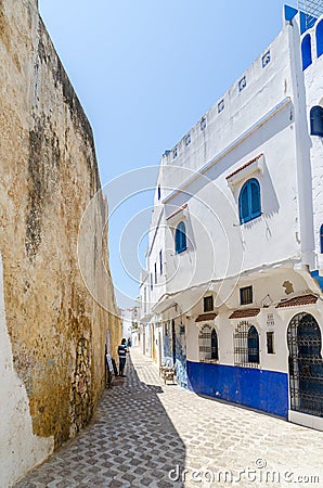 Stone alley with historic city wall and white and blue washed buildings in Asilah, Morocco, North Africa Editorial Stock Photo