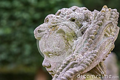 Stone angel statue in garden. Guardian angel statue in sunlight as a symbol of love in garden. Stock Photo