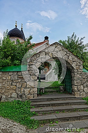 Stone arch entrance with steps to the orthodox church. Roofs and domes with crosses against the blue sky. Russia, summertime Stock Photo