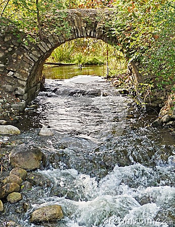 Stone arch over rushing stream Stock Photo