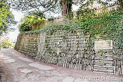 Stone based slope with wooden fance on it and the old road Stock Photo