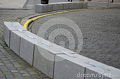 Stone blocks connected by metal strips. The unit acts as a road barrier with traffic arrows in a bend. A heavy chain protects the Stock Photo