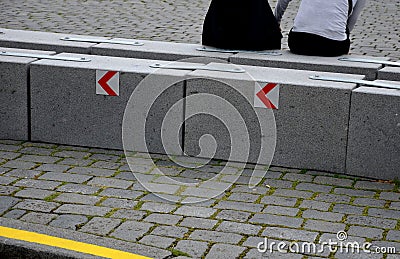 Stone blocks connected by metal strips. The unit acts as a road barrier with traffic arrows in a bend. A heavy chain protects the Stock Photo