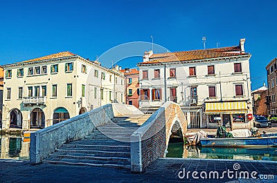 Stone brick bridge Ponte Pescheria across Vena water canal and old buildings in historical centre of Chioggia Stock Photo