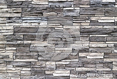Stone cladding wall made of striped stacked slabs of natural rocks. Colors are dark gray and white Stock Photo