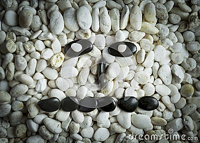 Stone faces small black and white stones with sad happy and angry faces Stock Photo