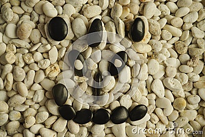 Stone faces small black and white stones with sad happy and angry faces Stock Photo
