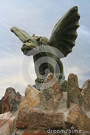 A stone gargoyle on a stone fence stands watch. Stock Photo