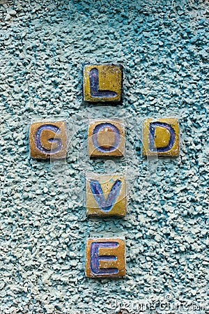 Stone graved text crossing of GOD LOVE on rough texture wall, vertical shot Stock Photo