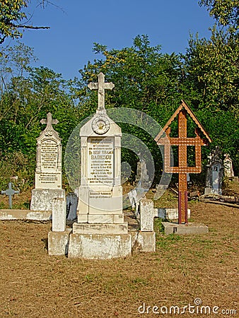 Stone gravetombs and woorden cross on a cemetery in the Romanian countryside Editorial Stock Photo