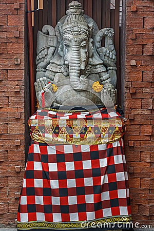 Stone Hindu Ganesha statue in sarong, decorated with Marigold flowers. Bali, Indonesia. Stock Photo