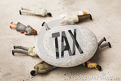 A stone with an inscription lies on toy men made of plastic, the concept of taxes crushes people Stock Photo