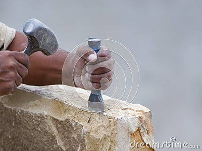 Stone mason chiseling a block of stone Stock Photo