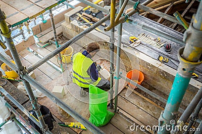 Stone Mason at work on major roof renovation of historic building at Dyrham Park, Gloucestershire, UK Editorial Stock Photo