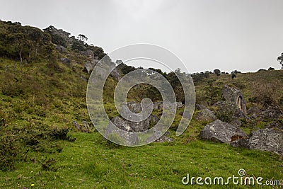 Stone monoliths countrysidelandscape with cloudy forest and rainy sky Stock Photo