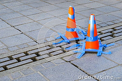 Stone patio with orange safety cones and blue painters tape blocking off loose bricks Stock Photo