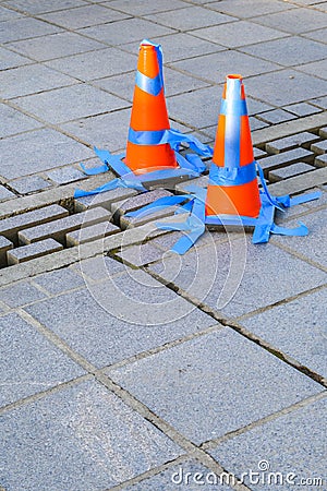 Stone patio with orange safety cones and blue painters tape blocking off loose bricks Stock Photo