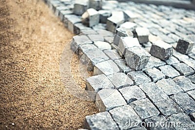 Stone pavement, construction worker laying cobblestone rocks on sand Stock Photo