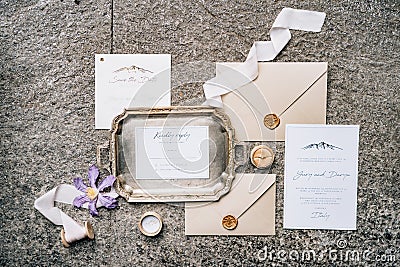 On the stone slab are wax-sealed envelopes, a metal tray, ribbons, flower and postcards. Top view Stock Photo