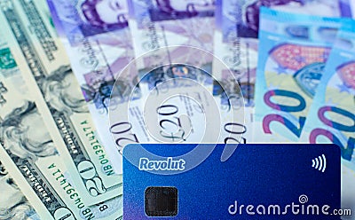 Close up photo of Revolut bank card on the dollar, pound, euro banknotes background. Illustrative concept of multi currency accoun Editorial Stock Photo