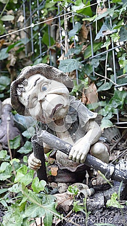Stone statue of a troll standing in the border of the garden Stock Photo