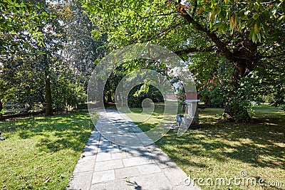 Stone tiled path with garden and chestnut trees in a sunny day, Italy Stock Photo