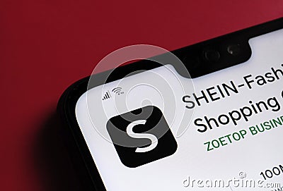 Stone / UK - July 14 2020: SHEIN app fashion shopping online platform seen on the corner of smartphone which is placed on the red Editorial Stock Photo