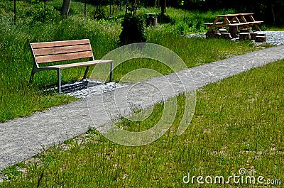 Stone walkways through a nature park made of irregular pieces. There are scabs on the pavement and around there are logs on which Stock Photo