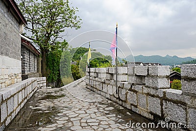 Stone wall with battlements and flags after rain in cloudy after Stock Photo