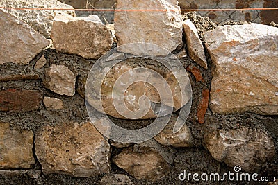 Stone wall during construction and masonry tools Stock Photo