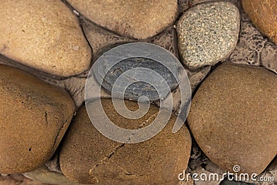 Stone wall is made of round and oval cobblestones and interconnected by cement Stock Photo