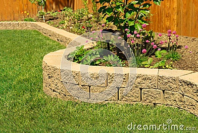 Stone wall with perfect grass landscaping in garden with artificial grass Stock Photo