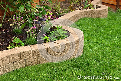 Stone wall with perfect grass landscaping in garden with artificial grass