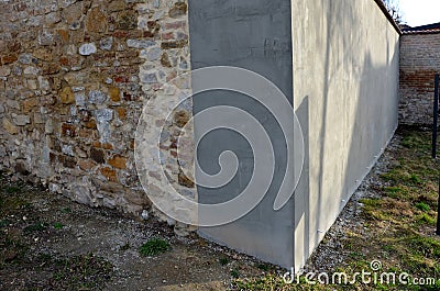The stone wall surrounding the garden is restored on one side with cement plaster. landscaping in the courtyard. gray smooth surfa Stock Photo