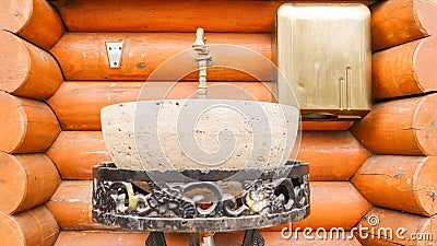 A stone washbasin on a metal forged stand in a log house. Interior in a house made of wood Stock Photo