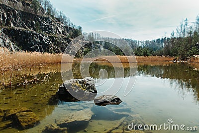 Stone in water in swamped quarry with high dry grass and rock, Czech republic Stock Photo