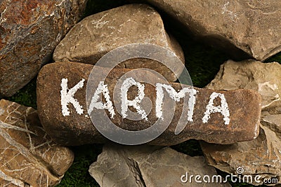 Stone with word Karma on green grass, above view Stock Photo