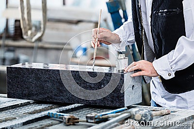 Stonemason painting in engraving with silver paint Stock Photo