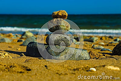 Stones pyramid on sand symbolizing zen, harmony, balance. Ocean in the background Stock Photo