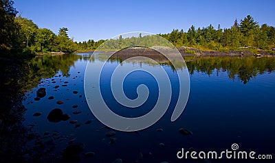 Stones in Still Blue River Stock Photo