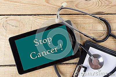 Stop Cancer - Workplace of a doctor. Tablet, stethoscope, clipboard on wooden desk background. Top view Stock Photo