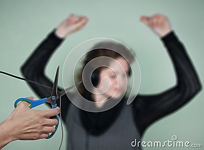 Stop listening to music! A hand with scissors cuts the wire from the headphones to a dancing girl. Concept of censorship, Stock Photo